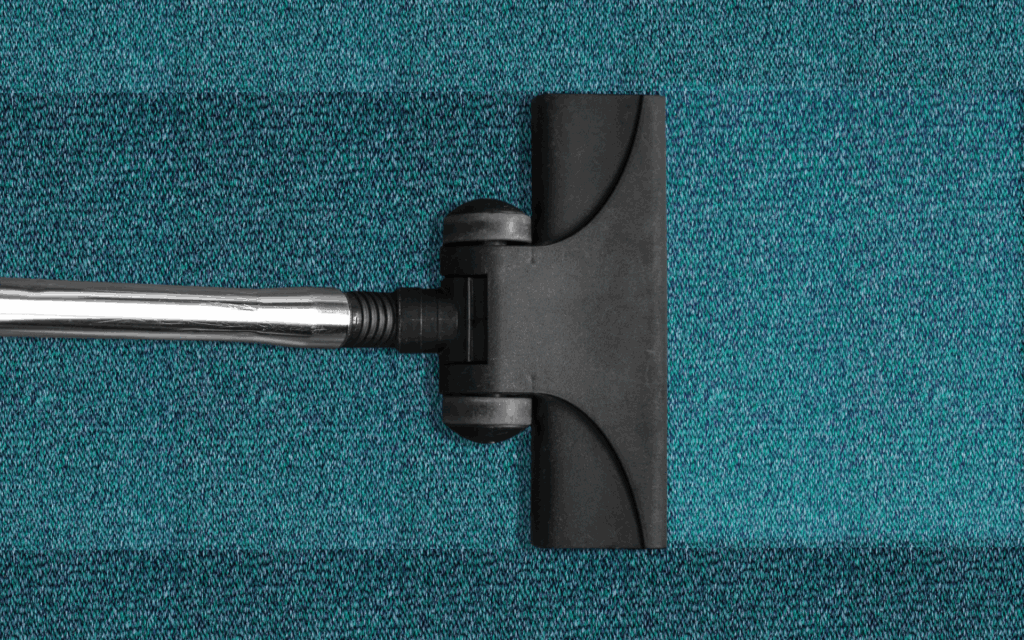Vacuum cleaner head cleaning a blue carpet with visible difference in cleanliness.