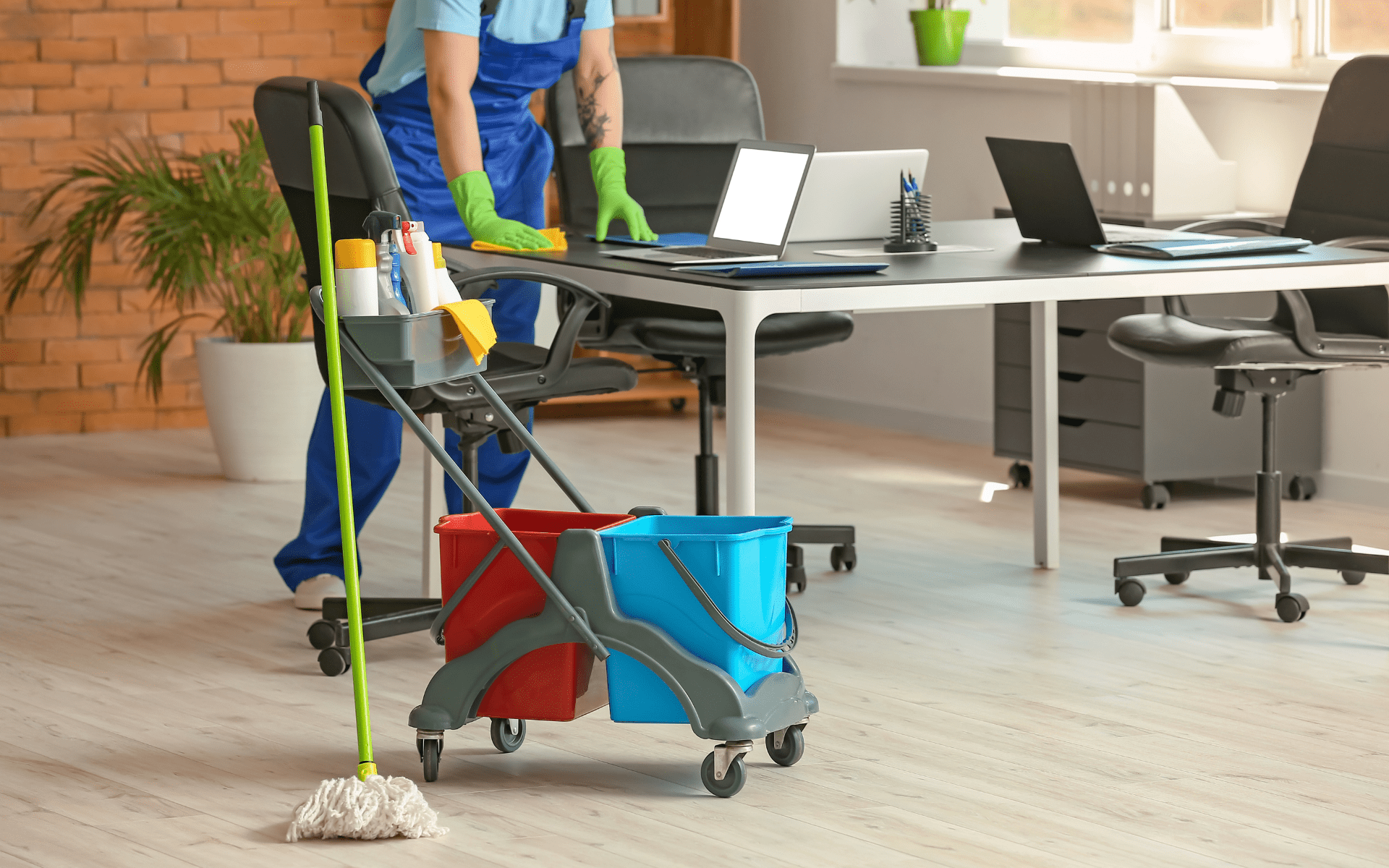 Commercial office cleaning service with janitor disinfecting desk and workstation.