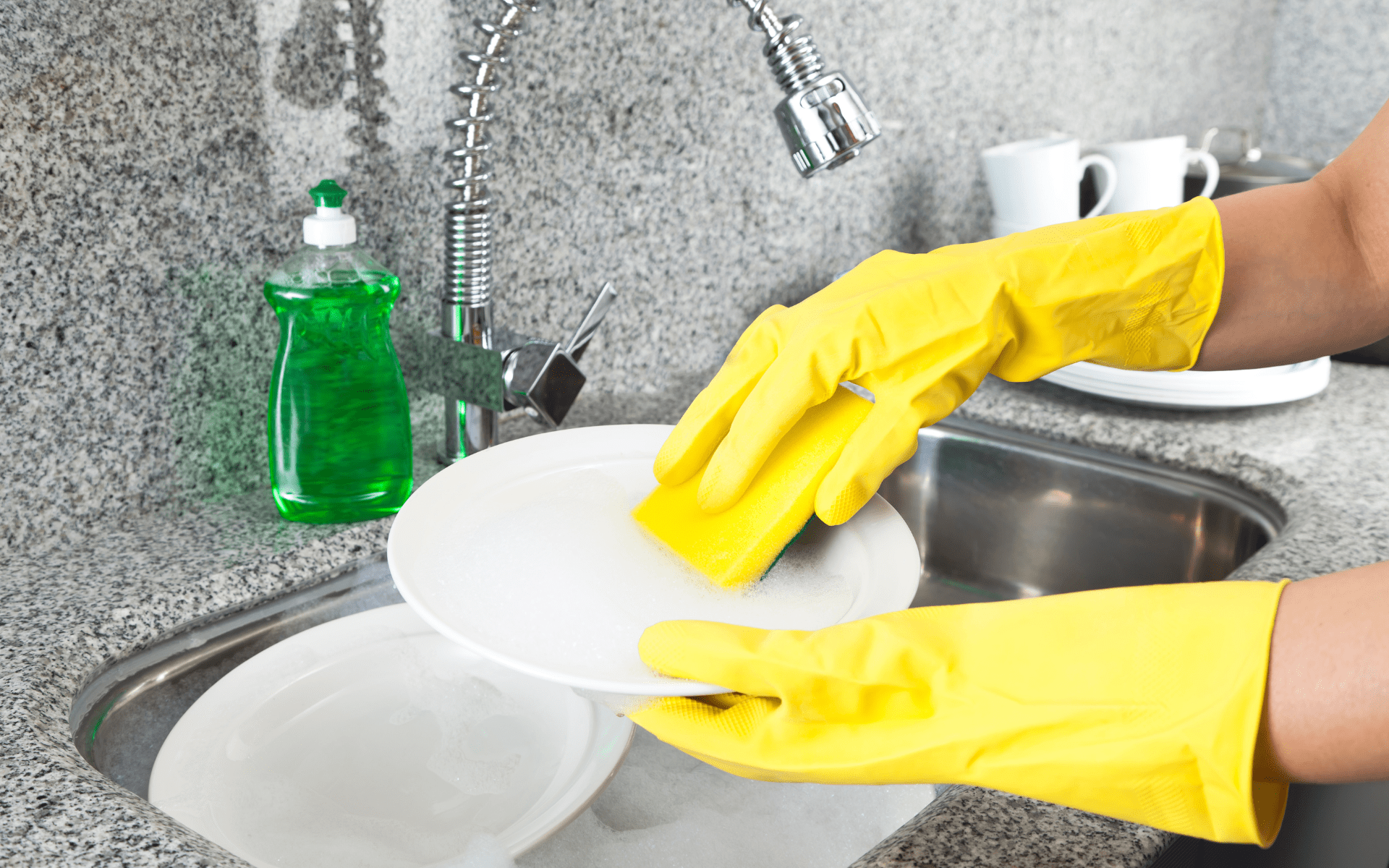 Washing and rinsing dishes with soap and sponge.