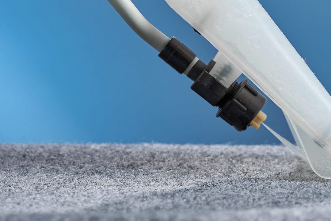 Horizontal shot of washing carpet with vacuum cleaner close-up on a blue background.
